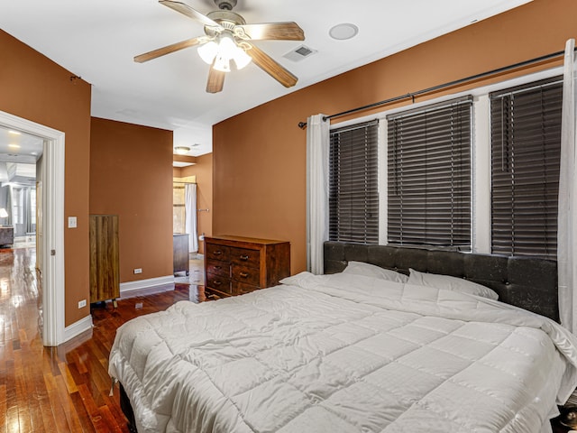 bedroom with dark hardwood / wood-style flooring, ceiling fan, and multiple windows