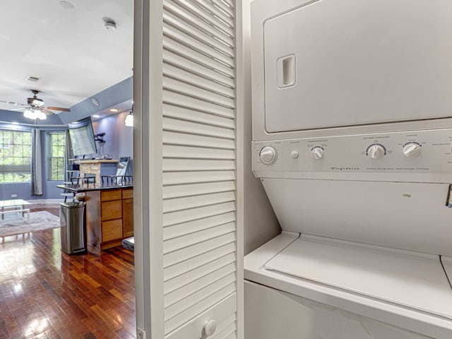 laundry room with ceiling fan, stacked washer / dryer, and dark hardwood / wood-style flooring