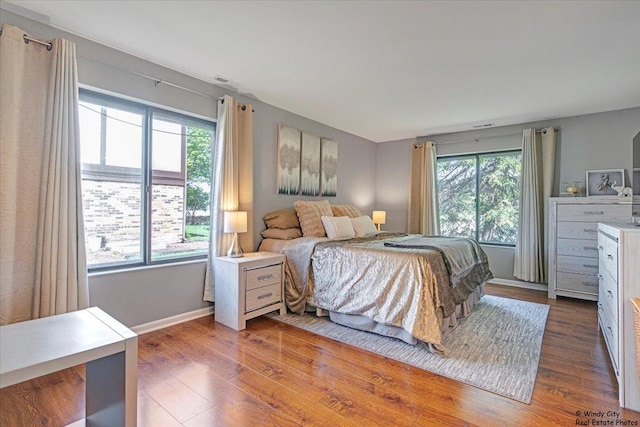 bedroom featuring baseboards, visible vents, and wood finished floors