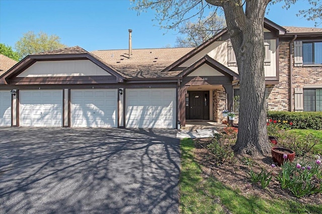 view of front of home with an attached garage, roof with shingles, driveway, and brick siding