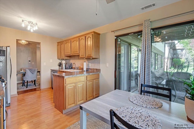 kitchen featuring visible vents, ceiling fan with notable chandelier, light wood-style floors, a sink, and appliances with stainless steel finishes