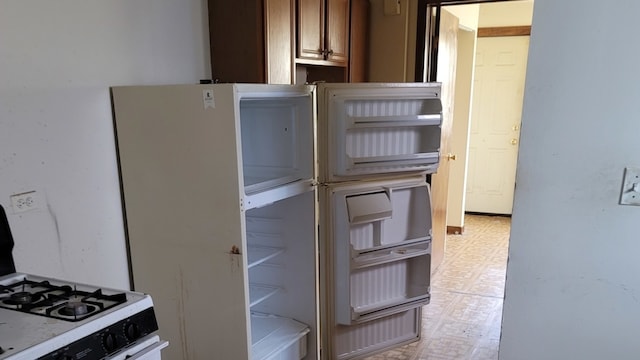 kitchen with white gas stove, light tile flooring, and fridge