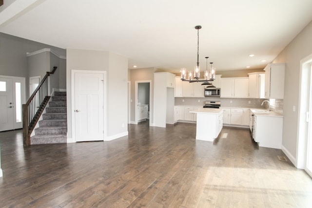 kitchen with dark wood-type flooring, stove, a kitchen island, white cabinets, and pendant lighting