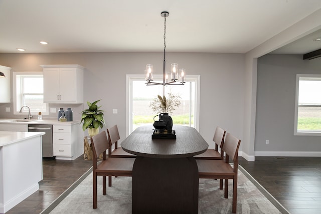 dining area with sink, a healthy amount of sunlight, a chandelier, and dark wood-type flooring