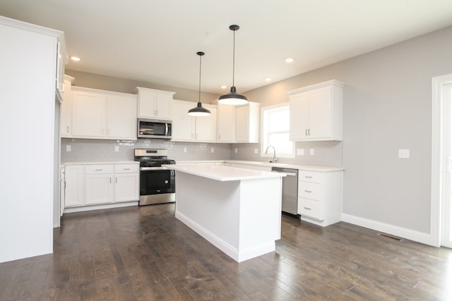 kitchen featuring dark hardwood / wood-style flooring, appliances with stainless steel finishes, white cabinets, decorative light fixtures, and backsplash