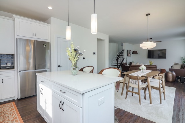 kitchen with a center island, open floor plan, freestanding refrigerator, white cabinetry, and dark wood-style flooring