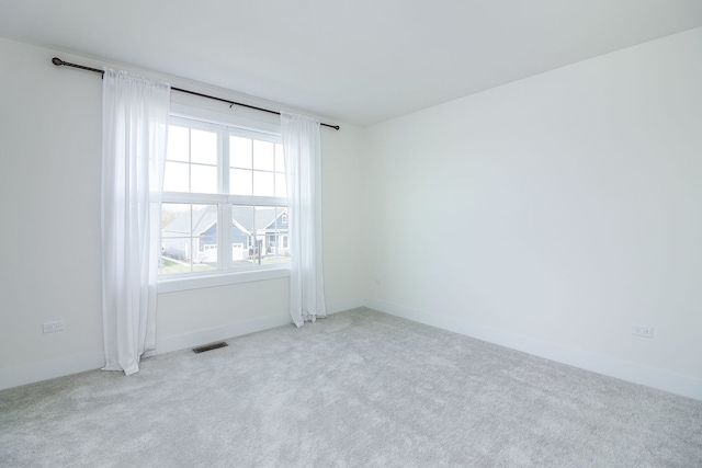 carpeted spare room with visible vents and baseboards