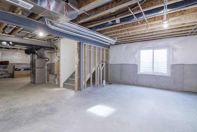 basement with heating unit, visible vents, and stairway