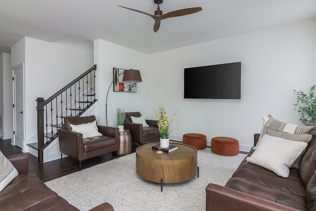 living room featuring stairway, baseboards, a ceiling fan, and wood finished floors