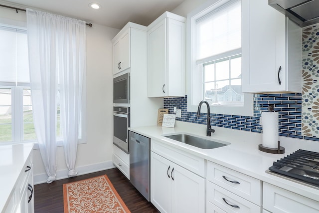 kitchen with a sink, stainless steel appliances, wall chimney exhaust hood, and light countertops