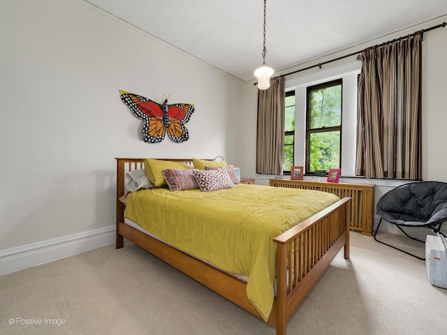 bedroom with baseboards, light colored carpet, and radiator