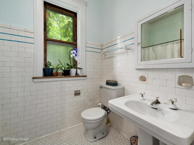 full bath featuring tile walls, toilet, and tile patterned floors