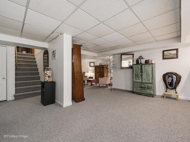 finished below grade area with a paneled ceiling, stairs, baseboards, and carpet flooring