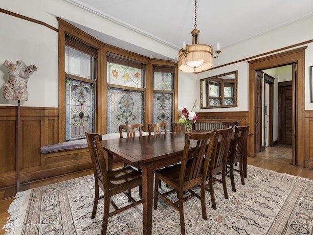 dining space with crown molding, wainscoting, and light wood-style floors