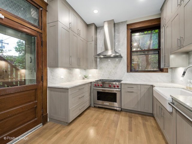 kitchen featuring light wood-style floors, wall chimney exhaust hood, designer range, and gray cabinets