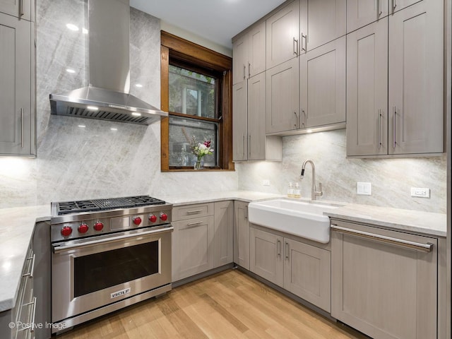 kitchen featuring gray cabinetry, a sink, premium stove, light wood-type flooring, and extractor fan