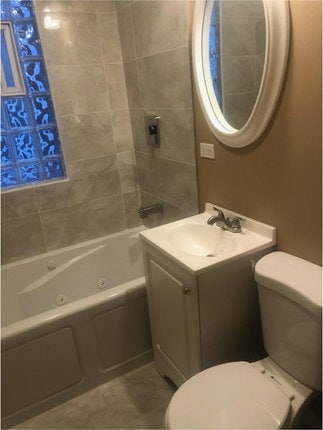 full bathroom featuring tiled shower / bath, vanity, toilet, and tile patterned flooring