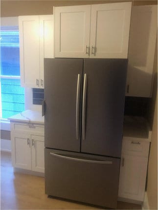 kitchen with stainless steel refrigerator and white cabinets