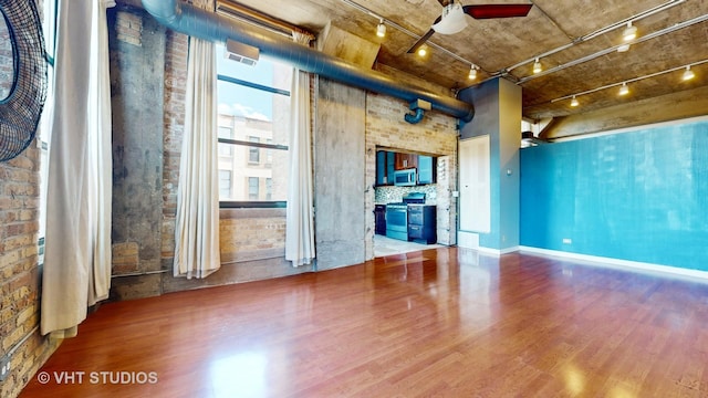 spare room with ceiling fan, brick wall, wood finished floors, and rail lighting