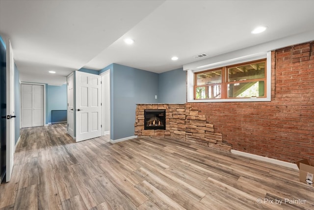 unfurnished living room with a stone fireplace and wood-type flooring