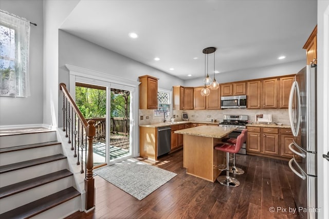 kitchen featuring appliances with stainless steel finishes, a center island, a kitchen bar, tasteful backsplash, and dark wood-type flooring