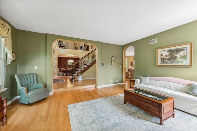 living area with arched walkways, wood finished floors, and baseboards