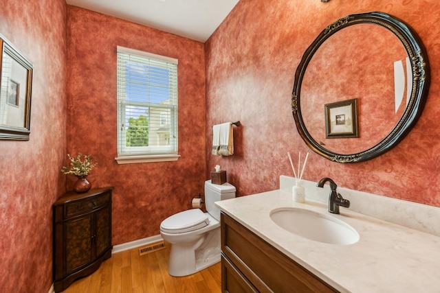 bathroom featuring wood finished floors, toilet, vanity, and baseboards