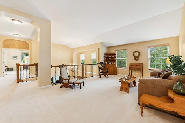 sitting room featuring carpet floors, an upstairs landing, baseboards, a chandelier, and arched walkways