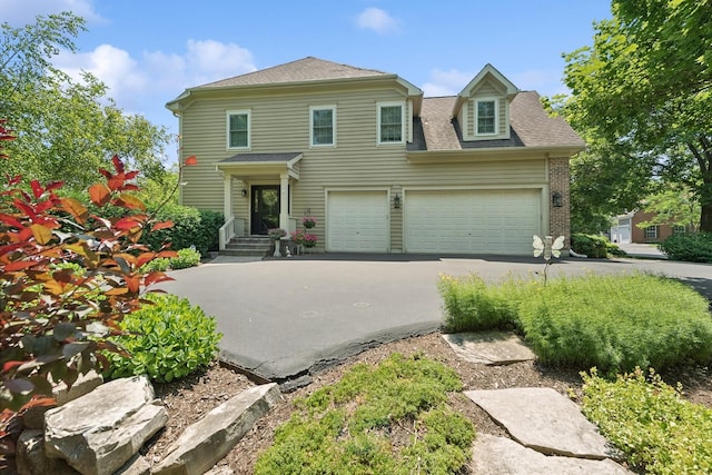 view of front of house featuring asphalt driveway, a shingled roof, and an attached garage