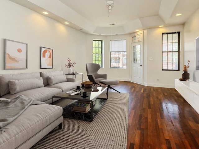 living room with ceiling fan, dark hardwood / wood-style flooring, and a tray ceiling