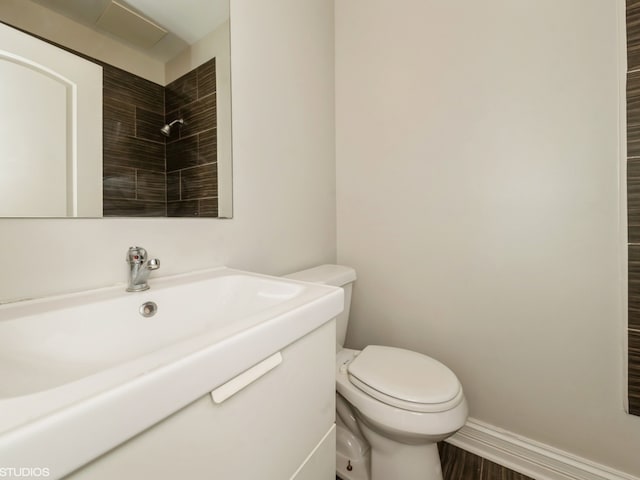 bathroom with a tile shower, hardwood / wood-style floors, and toilet