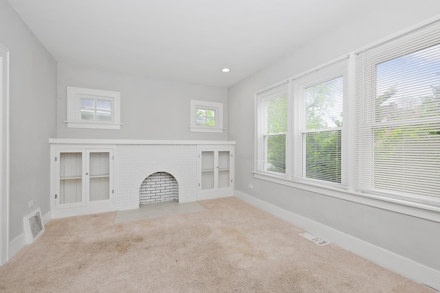 unfurnished living room with light carpet and a brick fireplace