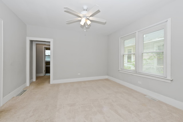 carpeted spare room with plenty of natural light and ceiling fan