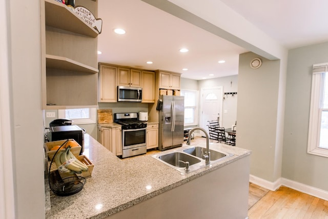 kitchen with a healthy amount of sunlight, sink, light hardwood / wood-style floors, light stone counters, and stainless steel appliances