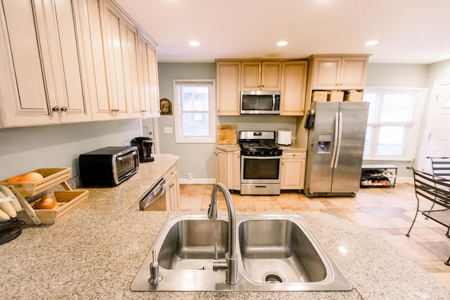 kitchen with sink, light brown cabinetry, light stone countertops, and appliances with stainless steel finishes