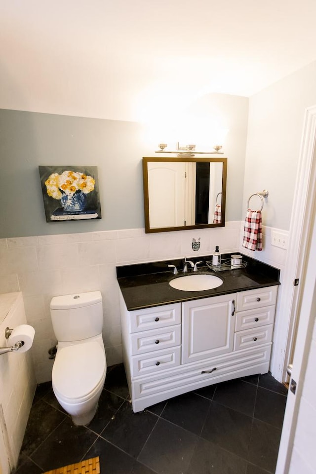 bathroom with tile patterned flooring, vanity, toilet, and tile walls