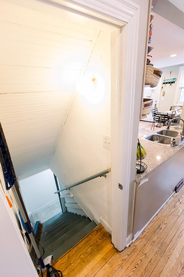 stairs featuring sink, wood-type flooring, and lofted ceiling