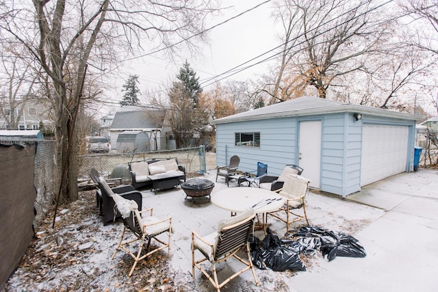 snow covered patio featuring an outdoor living space with a fire pit and an outdoor structure