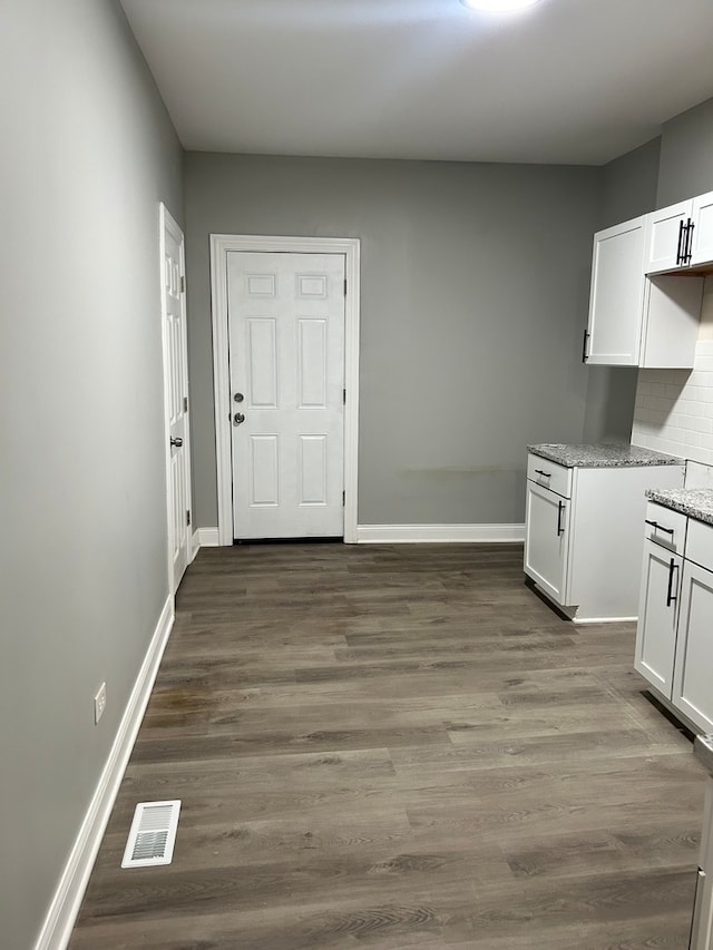 kitchen with hardwood / wood-style floors, light stone counters, tasteful backsplash, and white cabinets