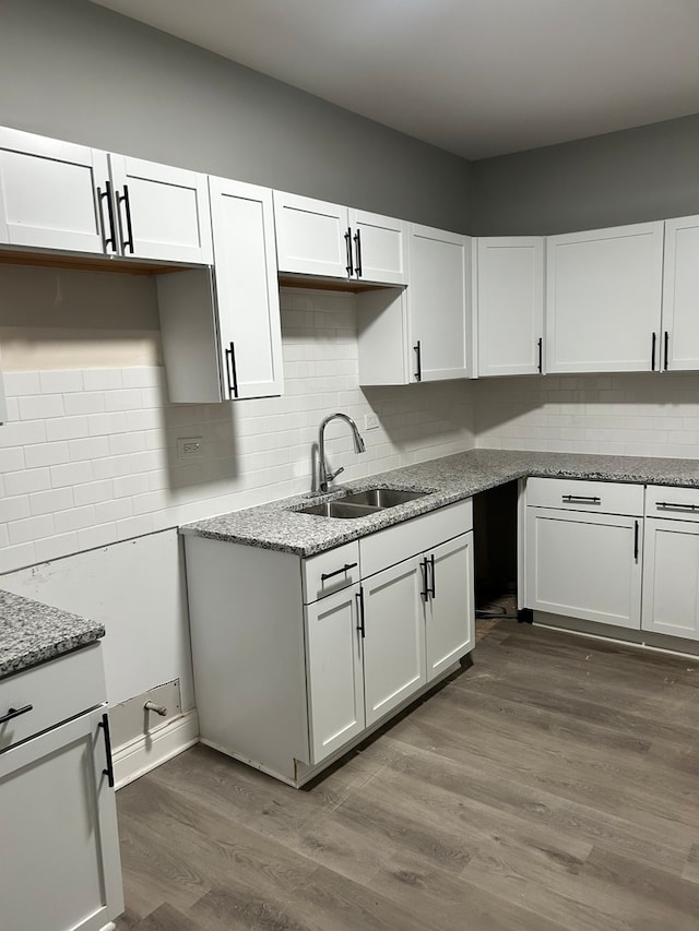 kitchen featuring sink, wood-type flooring, backsplash, and white cabinetry