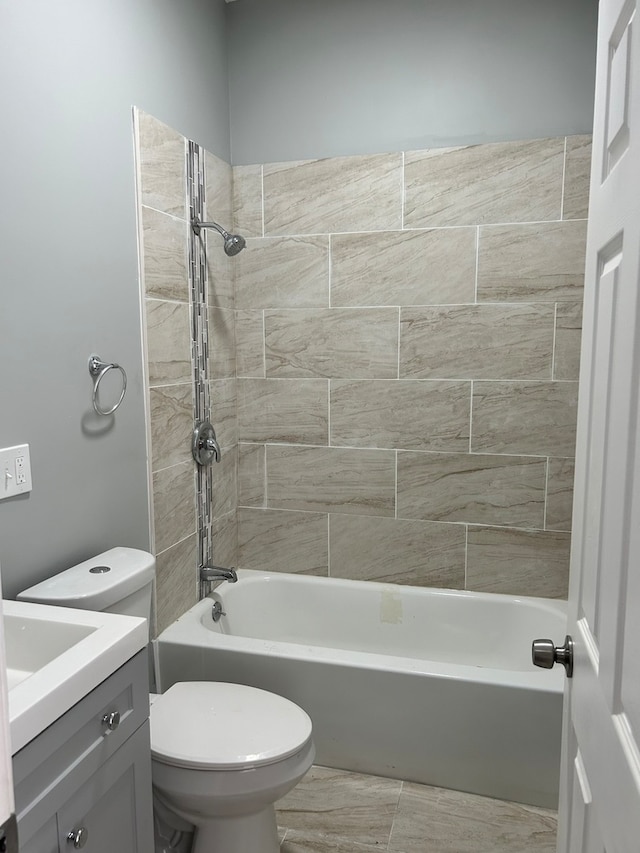 full bathroom featuring tiled shower / bath, toilet, tile floors, and vanity