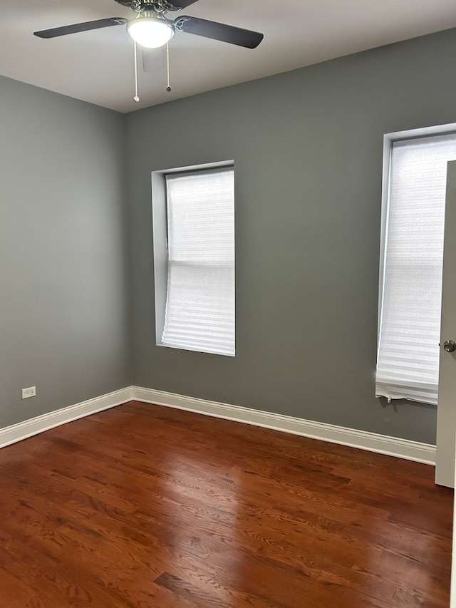 empty room with a wealth of natural light, ceiling fan, and dark hardwood / wood-style floors