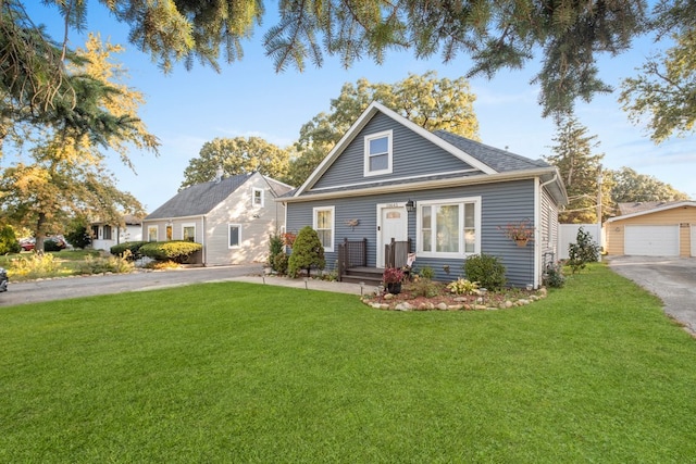 view of front of property featuring a front yard, a garage, and an outbuilding