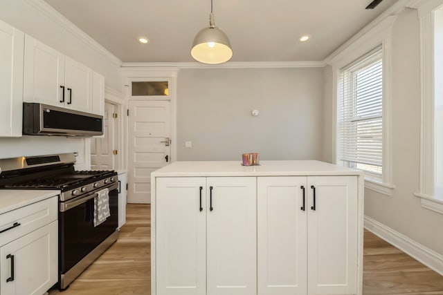 kitchen featuring a kitchen island, appliances with stainless steel finishes, decorative light fixtures, and light wood-type flooring