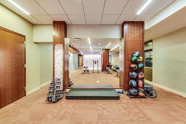 workout room with a paneled ceiling and carpet floors