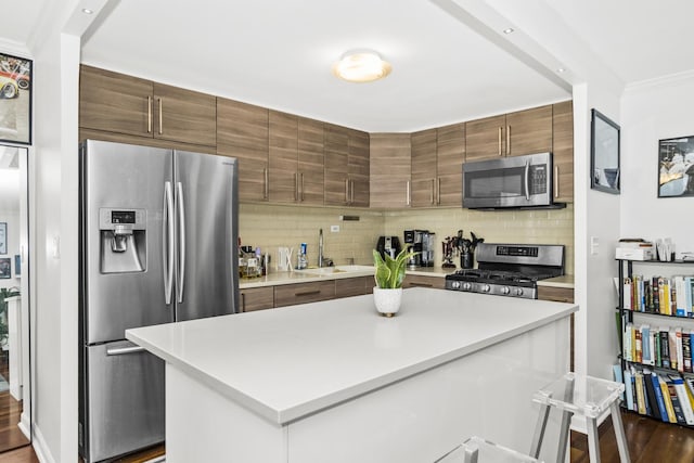 kitchen with sink, stainless steel appliances, a center island, ornamental molding, and decorative backsplash