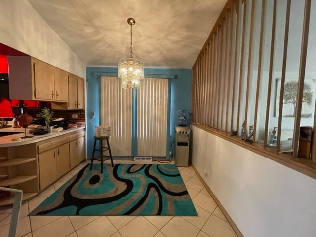 dining space featuring vaulted ceiling, a notable chandelier, and light tile flooring