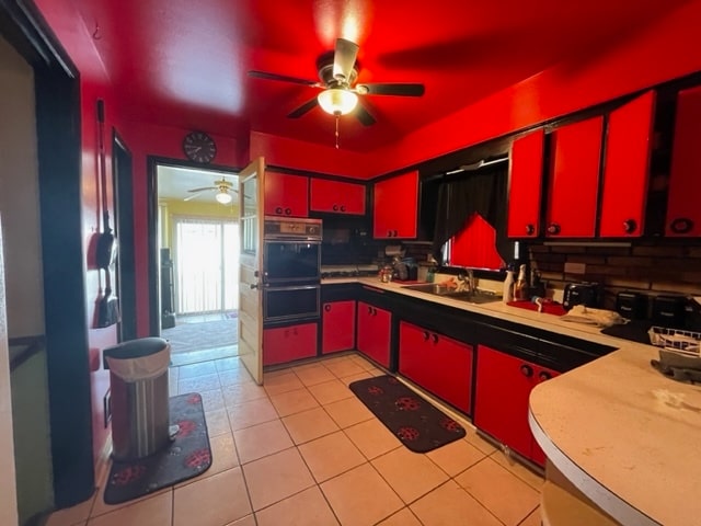 kitchen with backsplash, ceiling fan, sink, black double oven, and light tile floors