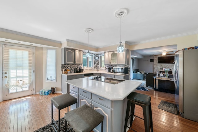 kitchen with a wealth of natural light, appliances with stainless steel finishes, a breakfast bar area, and light wood-type flooring