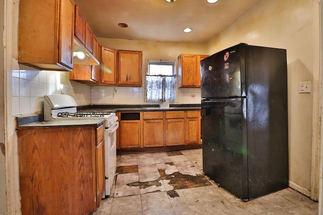 kitchen with tasteful backsplash, gas range gas stove, black refrigerator, and sink